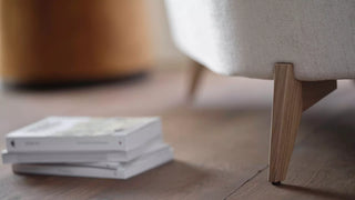 Detail van de houten poot en crème stof van een Mobitec Bolero fauteuil met tijdschriften