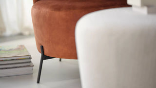 Detail van een roestoranje Mobitec Bolero poef en witte fauteuil