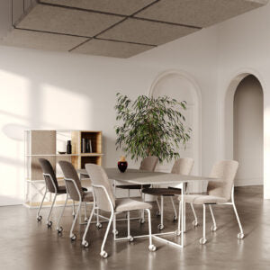 Lifestyle image of white Bejot Hens chairs around a table in a room with arched windows and a plant