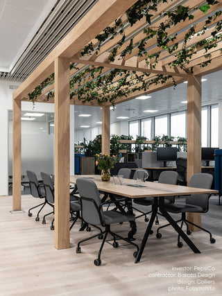 Lifestyle image of Bejot Hens chairs at a long table in an office with a plant ceiling