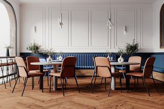 Lifestyle image of pink and wooden Bejot Hens chairs at tables in a restaurant with blue bench
