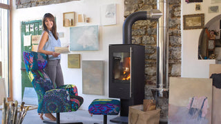 Lifestyle image of a woman by a colourful Mobitec Enora armchair next to a wood stove