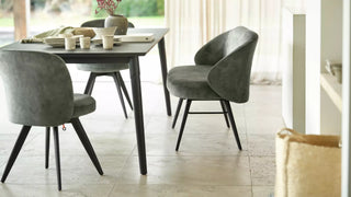 Sfeerbeeld van groene Mobitec Neo stoelen met zwarte poten aan een donkere eettafel