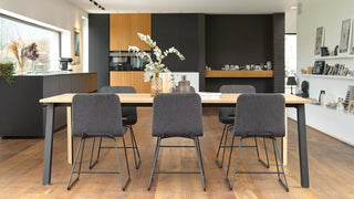 Sfeerbeeld van grijze Mobitec Pamp stoelen aan een houten eettafel in een open keuken