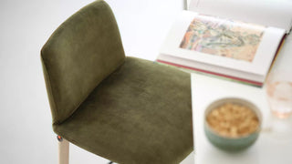 Detail of a green velvet Mobitec Rob stool with book and bowl