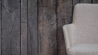 Detail of a light grey Mobitec Rob chair against a dark wooden wall