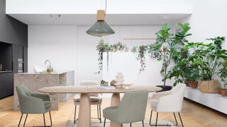Sfeerbeeld van groene Mobitec Saga stoelen aan een ronde houten tafel in een keuken met planten