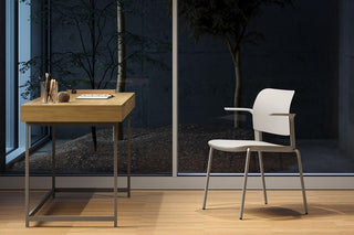 Lifestyle image of a white Bejot Volo chair at a wooden desk by a glass wall at night