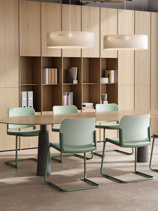 Lifestyle image of mint green Bejot Volo cantilever chairs at a wooden table with bookcase