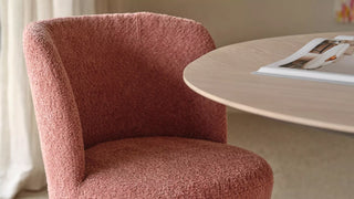 Detail van een roze bouclé Mobitec Bolero fauteuil aan een ronde tafel