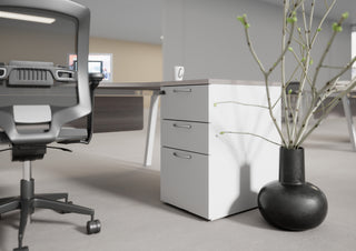 Photo d'ambiance d'un caisson hauteur bureau Buronomic Comfort blanc à côté d'un vase noir
