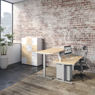 Lifestyle image of a Buronomic Locker Eko unit in white and beech by a sit-stand desk and brick wall