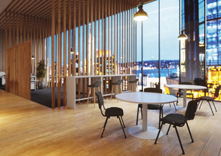 Sfeerbeeld van zwarte Buronomic Pratique stoelen rond een ronde tafel bij houten lamellen