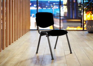 Sfeerbeeld van een zwarte Buronomic Pratique stoel met stoffen rug voor een stadsraam bij nacht