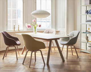 Sfeerbeeld van een eiken HAY CPH 30 tafel met groene en bordeaux stoelen in een lichte eetkamer