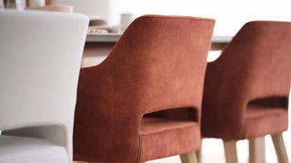 Detail van roestrode Mobitec Lena stoelen met open rug aan een tafel