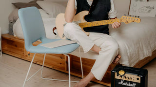 Sfeerbeeld van een lichtblauwe Mobitec Pamp stoel in een slaapkamer met gitarist