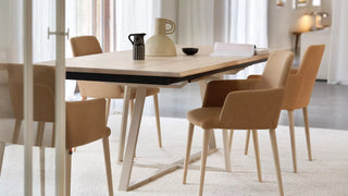Sfeerbeeld van cognac Mobitec Rob armstoelen aan een houten tafel in een lichte eetkamer
