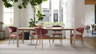 Sfeerbeeld van roze Mobitec Toro stoelen aan een lange houten tafel in een lichte ruimte